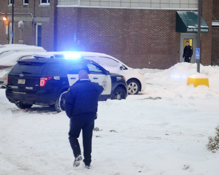 Police approach an entrance of the former MaineGeneral Medical Center in Augusta on Monday a few minutes after an officer-involved shooting in an office in the building.