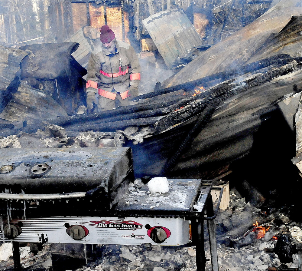 Pleasant Ridge firefighter Stanley Giguere walks through the smokey and burning remains of a home that was destroyed by fire early Wednesday morning in Pleasant Ridge.
