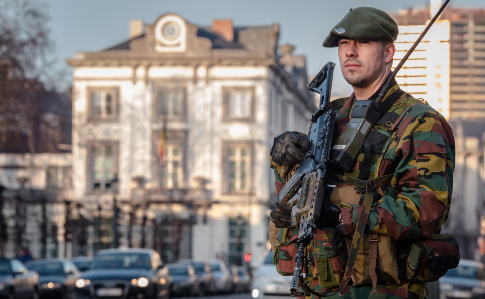 A Belgian para-commando patrols near the office of the prime minister in Brussels on Saturday. Security around Belgium has been stepped up since 13 people were detained.