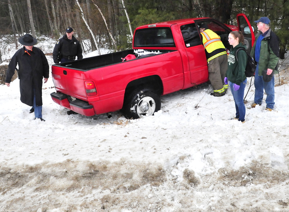 Paramedics lean into this truck to treat the driver after the vehicle went off Route 139 in Benton during freezing rain storm on Sunday.