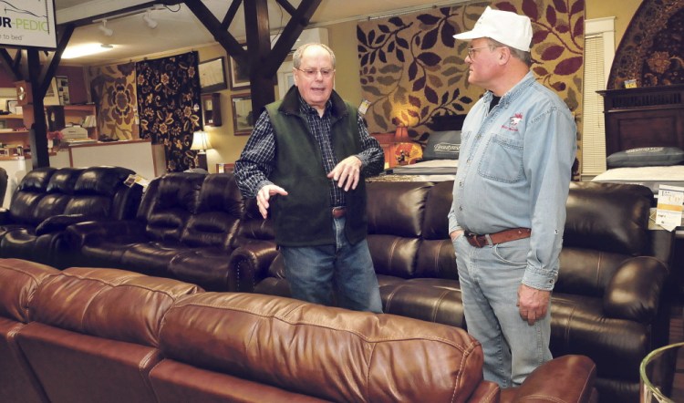 John Hamelin, left, of Hamelin’s Furniture in Waterville speaks with customer Brian Whitney on Thursday. Hamelin said he’s “guardedly optimistic” about the future of his business.