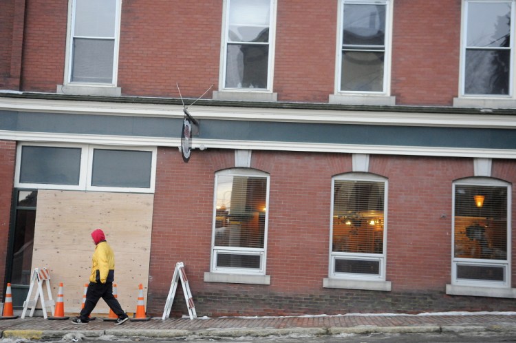 A man walks down Winthrop Street in Hallowell past a boarded up window at Hattie’s Chowder House on Monday. The restaurant was hit by a car Sunday night.