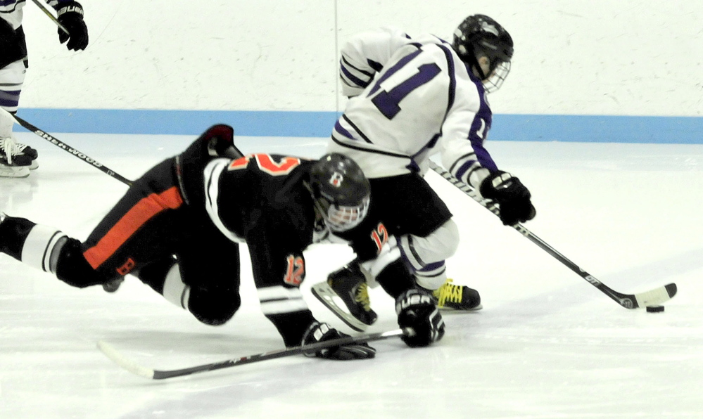 Waterville forward Jackson Aldrich, right, skates with puck after Brewer’s Tyler Davis falls to ice during an Eastern B game Monday afternoon in Waterville. The Purple Panthers doubled up the Witches, 6-3.