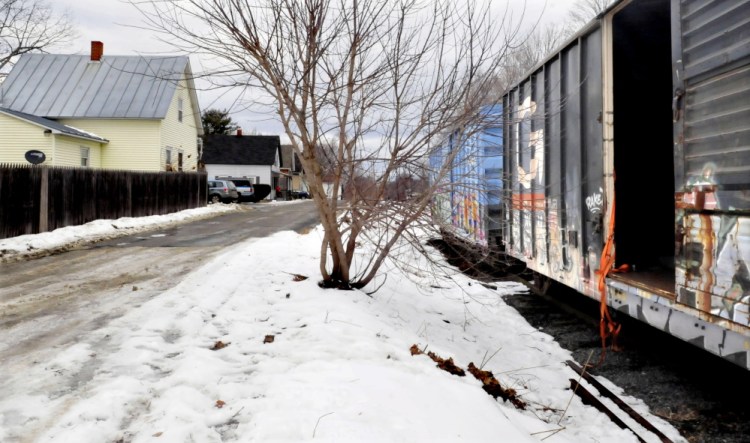 An open Pan Am railroad car stands along tracks on Monday near the home, at left, of Daniel and Jennifer Lally at 27 Railroad Ave. in Oakland. The Lallys have complained that the cars are being used at night by people who have left bedding, clothes and makeshift candles in them.