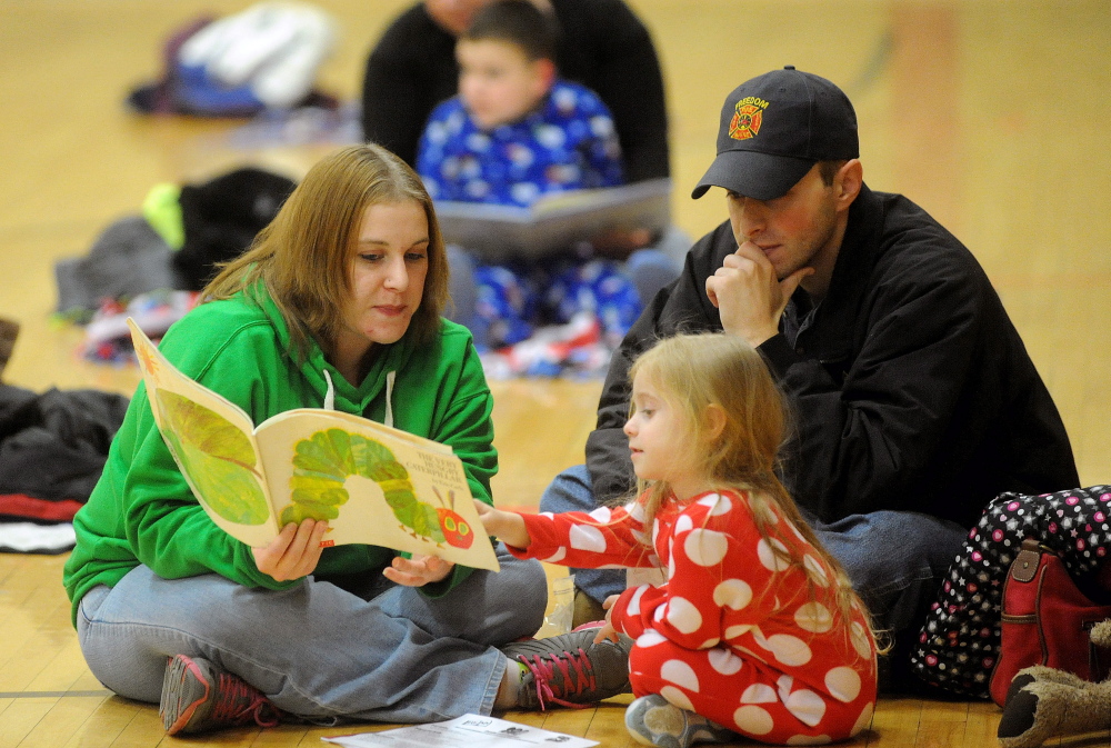 Keisha Whitman, left and husband Scott, right, read to their 4-year-old daughter Danica at Winslow Elementary School’s Books and Blankets event. Normal: