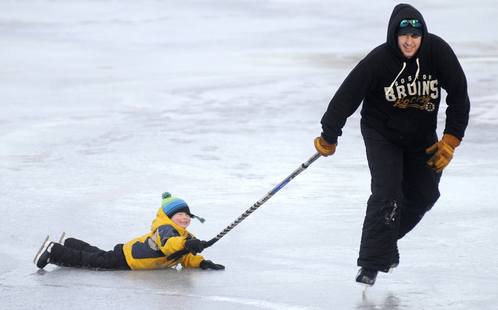 Aiden Lucas, 3, hitches a ride on a hockey stick pulled by his father, Matt, across Lake Cobbossee in Manchester, in between monitoring their ice fishing traps in January 2015. The Augusta residents caught one pickerel.
