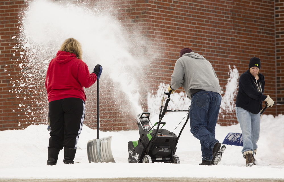 Saco Middle School custodians Lodel Seneres, Joi MacDonald and Donna Jose, clear snow from Saturday’s storm on Sunday. They will have more work ahead as a nor’easter is expected to dump at least a foot of snow Monday night through Wednesday morning.