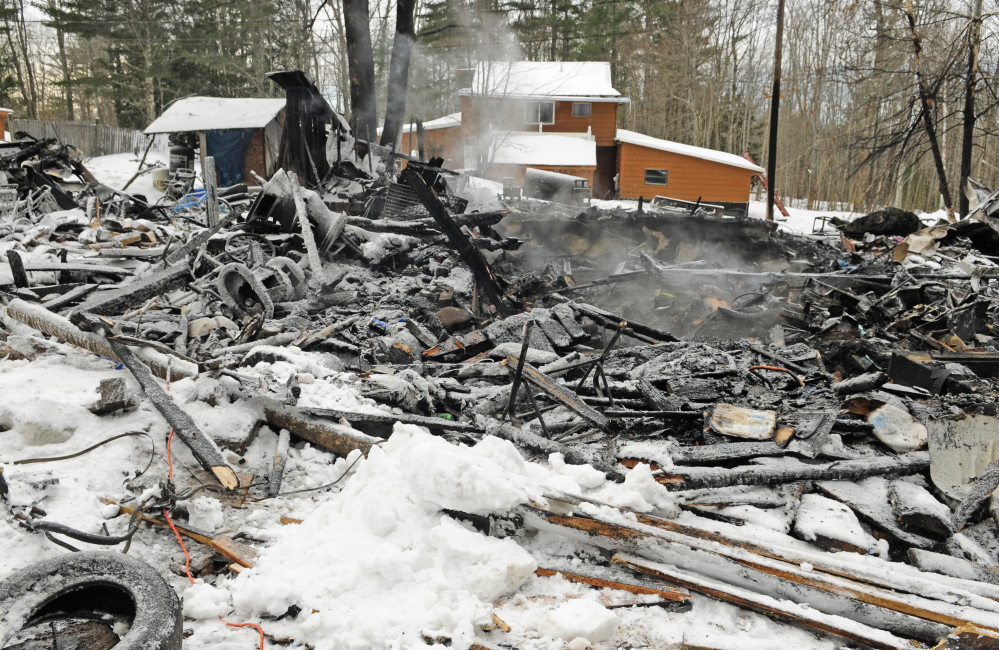 Steam rises from the remains of a house on Wednesday at 452 Mills Road in Whitefield. The house was destroyed by fire during the snow storm on Tuesday afternoon but firefighters from several departments stopped it from spreading to Michael Farrell’s home, in background, about 50 feet away.