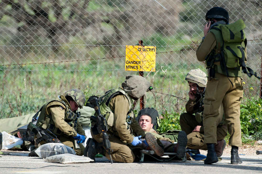 Israeli soldiers treat a wounded soldier near the Israel-Lebanon border, Wednesday.