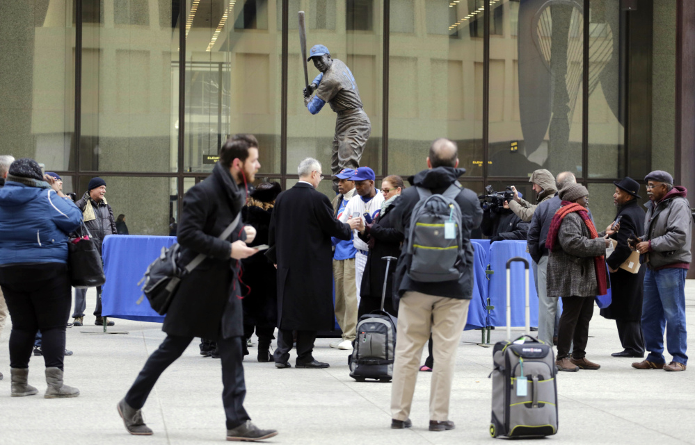 Baseball fans gather around the statue of Chicago Cubs Hall of Famer Ernie Banks that was placed in Daley Plaza, as fans get their first chance to pay their respects, Wednesday in Chicago.