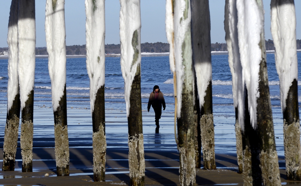The Pier’s pillars in Old Orchard Beach, covered in snow and ice, reflect the cold and windy conditions that have prevailed this week. The weather gave way to sun on Thursday, allowing Elisa Jacobs of Needham, Mass., to take a stroll along the beach.