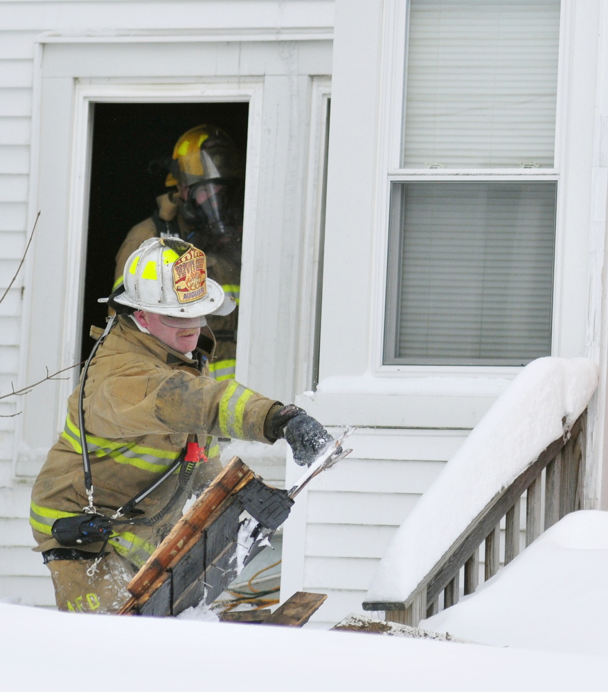 Augusta Deputy Fire Chief Dave Groder throws boards that another firefighter working inside passed out to him Saturday at 101 Green St. in Augusta. Firefighters tore out the boards to find any fire that might be remaining in floors and walls.