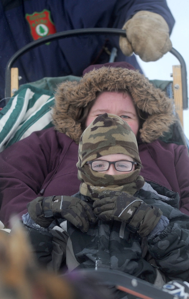 Mary Riopelle bundles up with her son Donald on Saturday as they brave the cold for a dog sled ride at the annual Winter Carnival at the Quarry Road Recreational Area in Waterville.