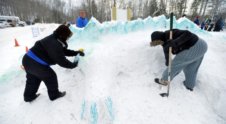 Jennifer Olsen, left, and Serena Sanborn create a dragon out of snow Saturday as part of the snow sculpture contest at the annual Winter Carnival at Quarry Road Recreational Area in Waterville.