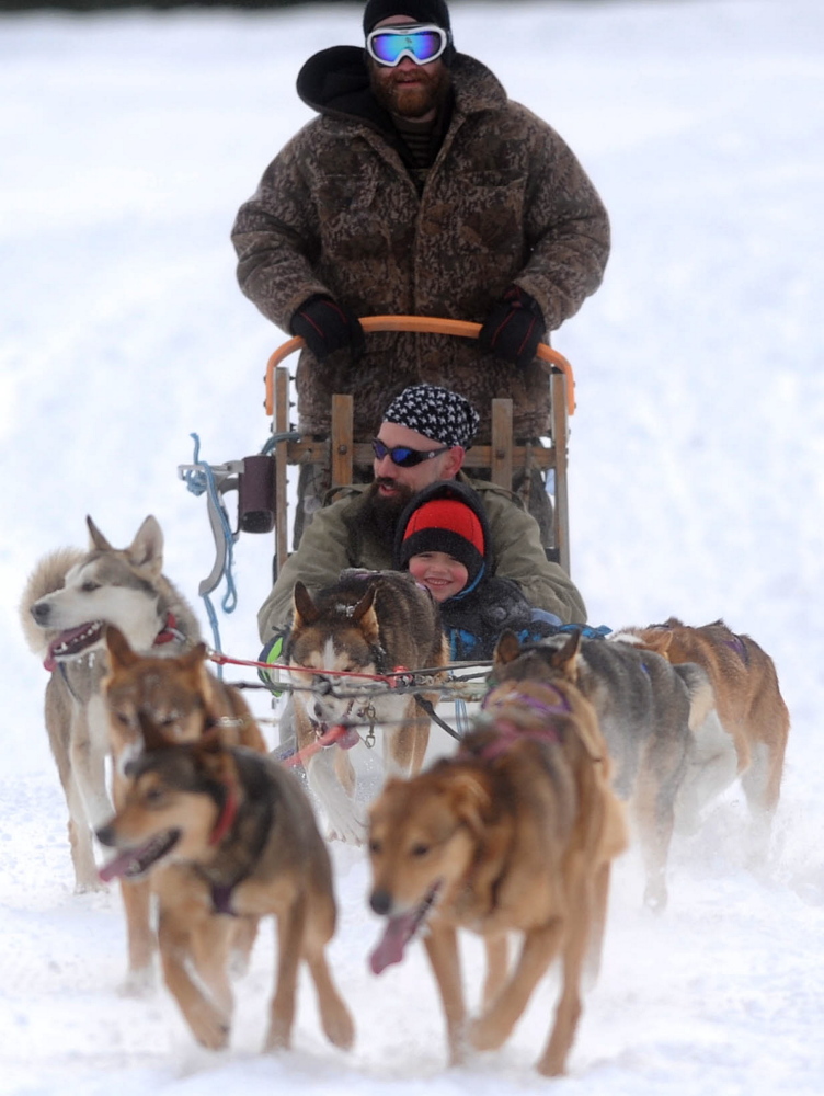 Tim Lonergan, a musher with Heywood Kennels in Augusta, drives a dog sled Saturday with Dominic Bunker and his nephew Landyn Cummings, 5, for the annual Winter Carnival at Quarry Road Recreational Area in Waterville.