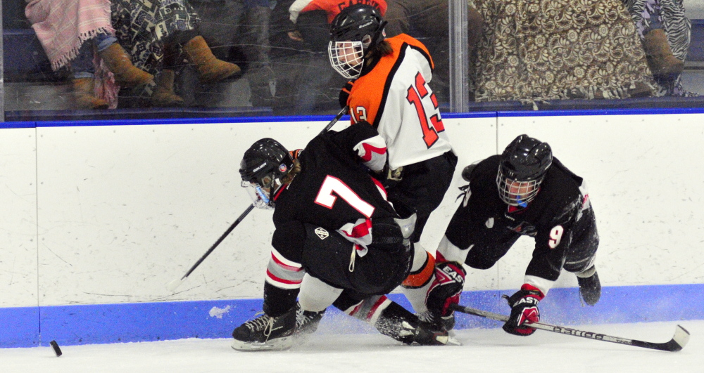 Maranacook/Winthrop’s Bailey Clark, left, Gardiner’s Tristan Hebert and the Hawks’ Austin Jones chase after the puck during a game on Saturday at the Bank of Maine Ice Vault in Hallowell.