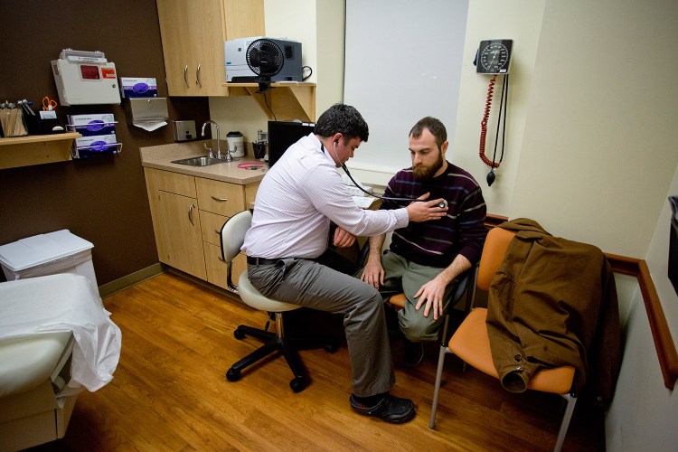 Dr. Brad Huot, a primary care physician at Martin's Point Health Care on Veranda Street in Portland, checks the heart rate of Tyson O'Keefe on Tuesday. The state announced that it will fill about an $8 million gap in federal funding to keep MaineCare reimbursements for physicians the same. Gabe Souza/Staff Photographer
