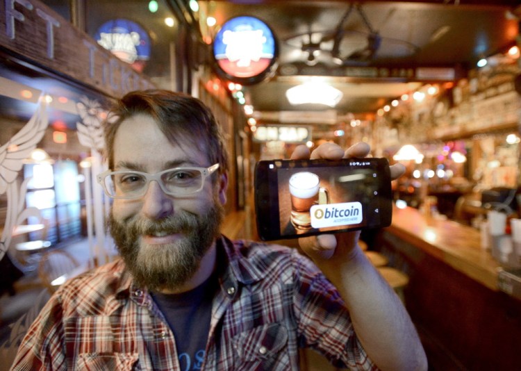 Dave Foster, media marketing manager at The Great Lost Bear in Portland, holds up his mobile phone displaying a bitcoin app that can be used for payment at his restaurant. John Patriquin/Staff Photographer