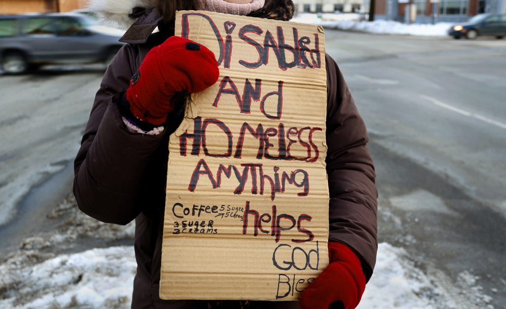 A panhandler holds a sign on the corner of Preble Street and Marginal Way in Portland. A city ordinance that bans people from standing on medians will be heard by a federal appeals court in Boston on Friday. 2013 Press Herald File Photo/Tim Greenway