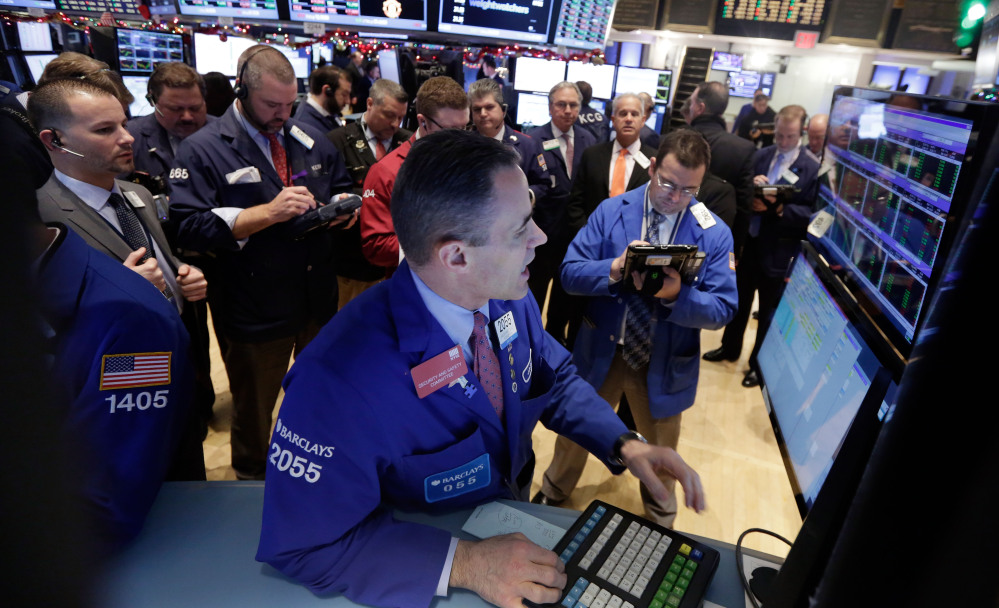 Traders gather at the post of specialist Jason Hardzewicz, foreground, on the floor of the New York Stock Exchange on Tuesday. The Associated Press