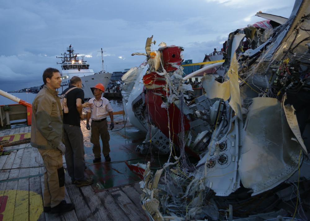 An Indonesian member of National Transportation Safety Board talk with a foreign investigator near part of the tail of AirAsia Flight 8501 on the deck of rescue ship Crest Onyx at Kumai port in Pangkalan Bun,Sunday. The Associated Press
