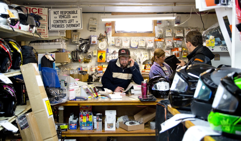 Wayne Keniston handles a call at his Falmouth store while shoppers anticipating good riding browse for snowmobile gear.  Gabe Souza/Staff Photographer