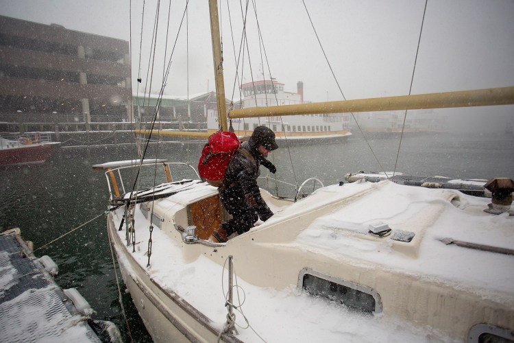 Jack Marrie enters his 30-foot fiberglass ketch Rime, where he lives year-round, during a blizzard Tuesday. Marrie said he did nothing special to prepare for the storm, and that winter can actually be easier than summer when it comes to living on a boat. Gabe Souza/Staff Photographer