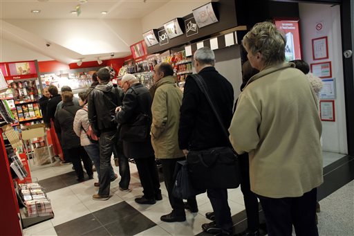 People queue up to buy the new issue of Charlie Hebdo newspaper at a newsstand in Paris Wednesday.Charlie Hebdo's defiant new issue sold out before dawn . The Associated Press