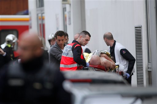 An injured person is treated by nursing staff outside the French satirical newspaper Charlie Hebdo's office, in Paris, Wednesday. The Associated Press