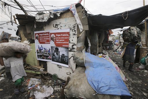 Filipinos pass posters with messages for Pope Francis as they carry plastics for recycling at a garbage dump northeast of Manila Tuesday.  The Associated Press