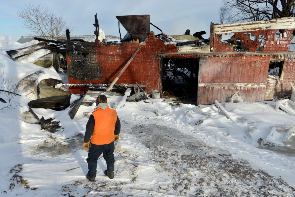 Fred Sherburne, former owner of Sherburne Farm in Dexter, on Tuesday walks past the barn that burned on Monday at the farm.