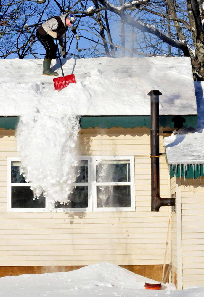 Bob Foster shovels snow from the rooftop of his home in Benton last Sunday. “I like to stay on top of this snow,” Foster said. More fell during the week, and Foster will have even more to deal with after forecast that there may be as much of a foot of new snow by Monday.
