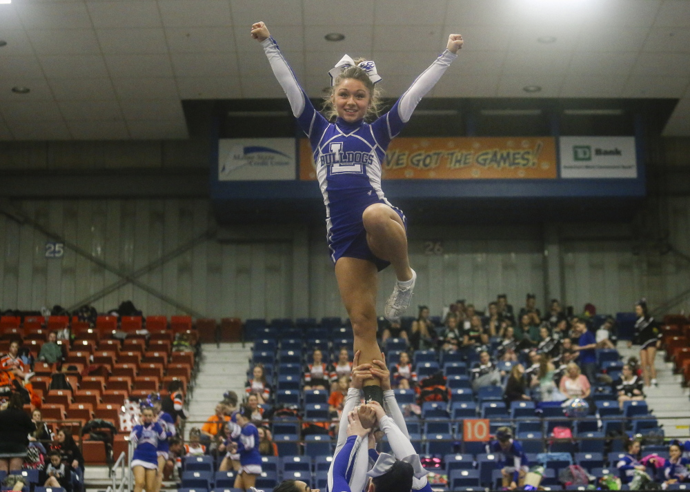 Maine Sunday Telegram photo by by Whitney Hayward 
 Lawrence sophomore Sierra Hawkes stands in formation as she's hoisted by teammates into the air during the Class A state championships Saturday at the Augusta Civic Center.