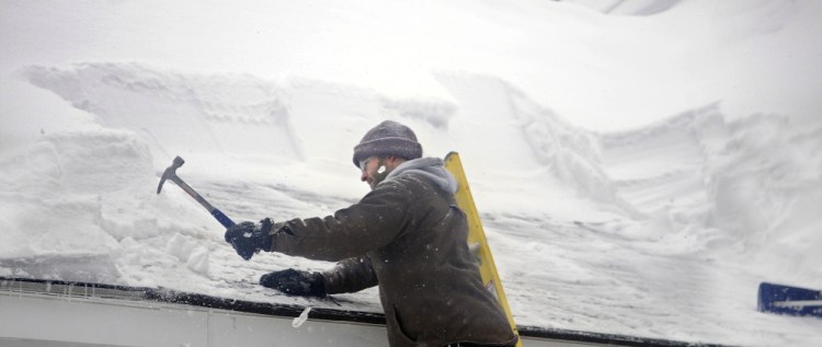 Jeff Mercier smashes ice dams on the roof of his Gardiner home on Sunday. The town of Athens native said the transition of moving this August with his wife back to Maine from California, where he served in the Marines, has been a challenge because of the snowy winter.