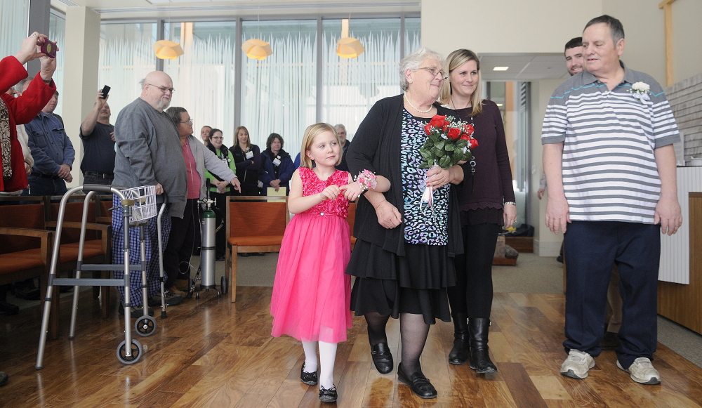 Esther Harris, second from left, is escorted Thursday by grand-niece McKenna Bishop, 5, and a niece, McKenna’s mother, Jennifer Bishop, to exchange wedding vows with Alan Gosselin, right, at the Spiritual Center at MaineGeneral Medical Center in Augusta.