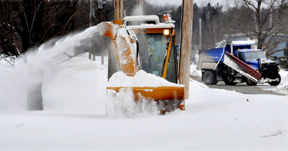 Josh Berryman, of the Skowhegan Highway Department, slowly clears a snow-filled sidewalk as a town plow truck passes nearby on Thursday. “This is rough going in this snow,” Berryman said.