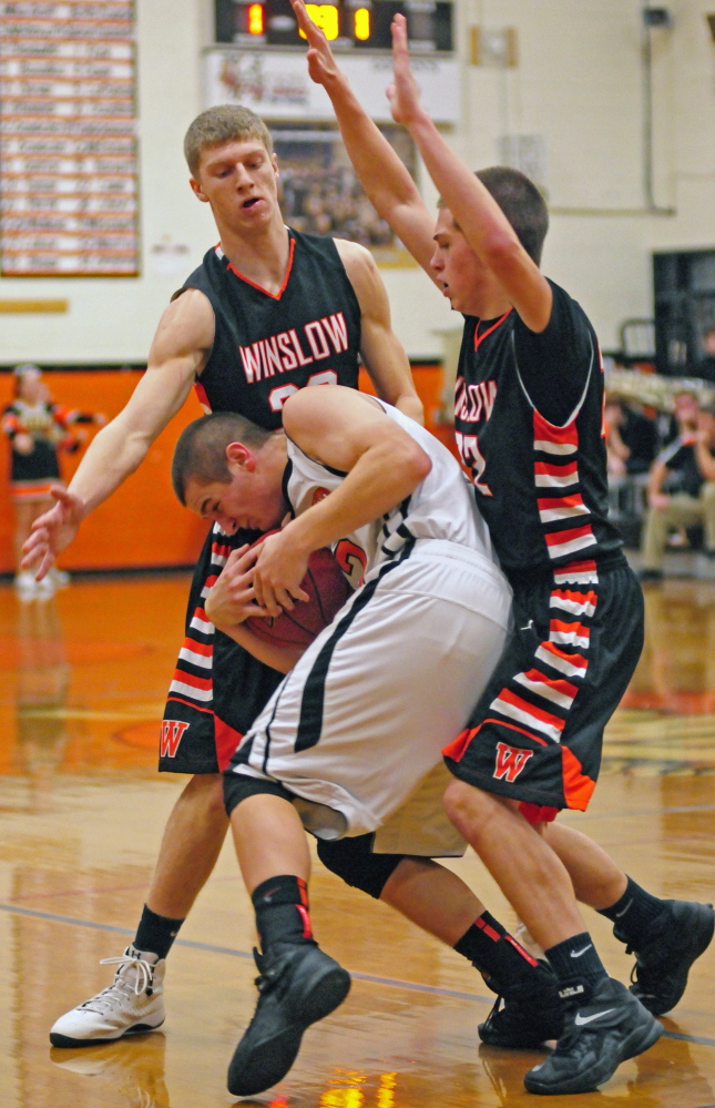 Staff file photo by Joe Phelan 
 Winslow's Justin Martin, left, and Josh Kervin, right, swallow up Gardiner's Seth McFarland during an Eastern B game Dec 12 in Gardiner. The Tigers and Raiders will play regional quarterfinal games Saturday in Bangor.