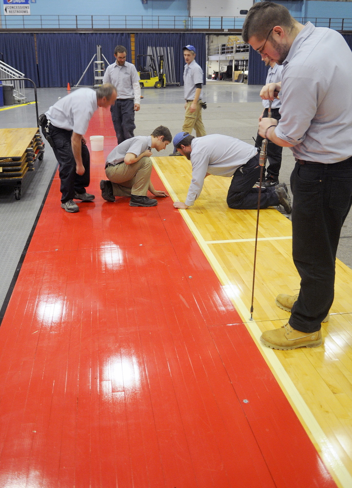 Augusta Civic Center employees put down the basketball court Tuesday. The civic center is replacing the high school floor with a college floor for the high school basketball tournament.