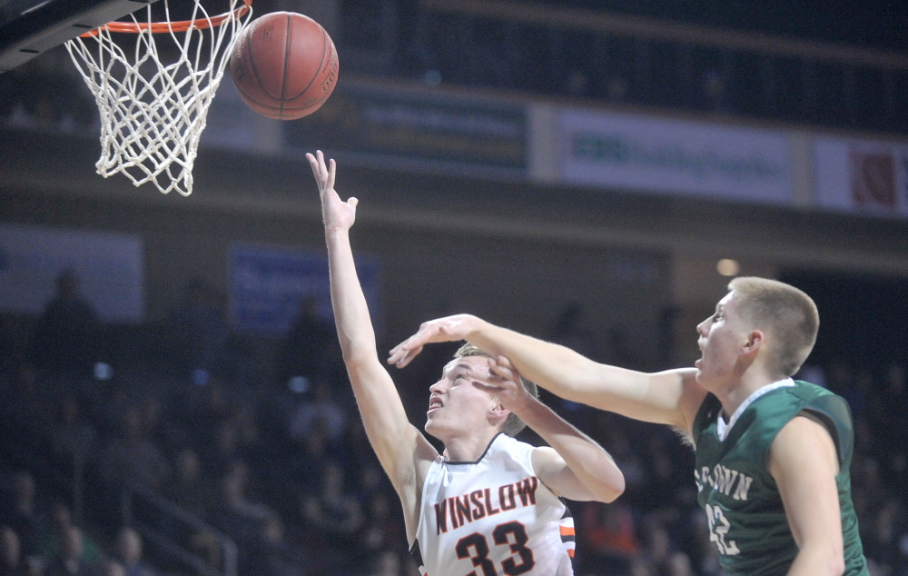 Winslow High School’s Justin Burgher, left, drives past old Town High School’s Adam Richardson in the first half of an Eastern B semifinal at the Cross Insurance Center in Bangor on Wednesday. Winslow prevailed 48-44.