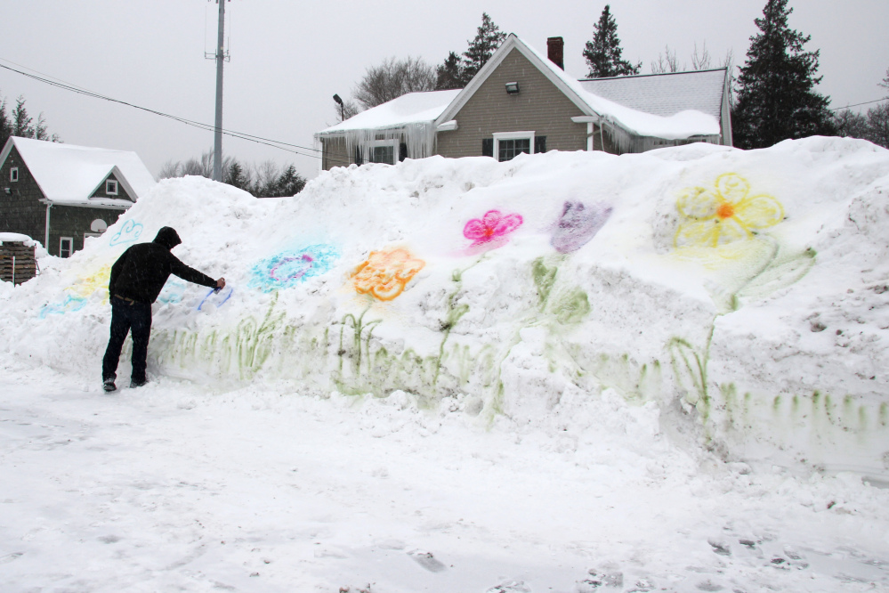 William Green, 25, spray paints flowers onto a snow bank in the parking lot of Genrich’s Garden Center where he works in Irondequoit, New York. This has been one of the coldest Februarys on record in the region with frigid temperatures and more snowfall forecast for the coming week, according to the National Weather Service.