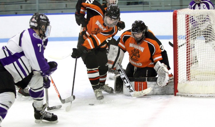 Winslow High School defenseman Dameron Rodrigue clears the puck in front of goalie Andrew Beals as Waterville’s Nick Denis, 7, skates toward the net during an Eastern B game Dec. 27, 2014. Beals and the Raiders will host Hampden on Tuesday in an Eastern B quarterfinal.