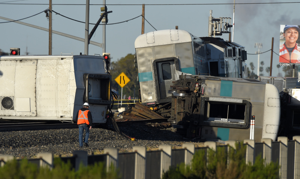 A worker walks along the tracks near the wreck of a Metrolink passenger train that derailed, Tuesday, in Oxnard, Calif.