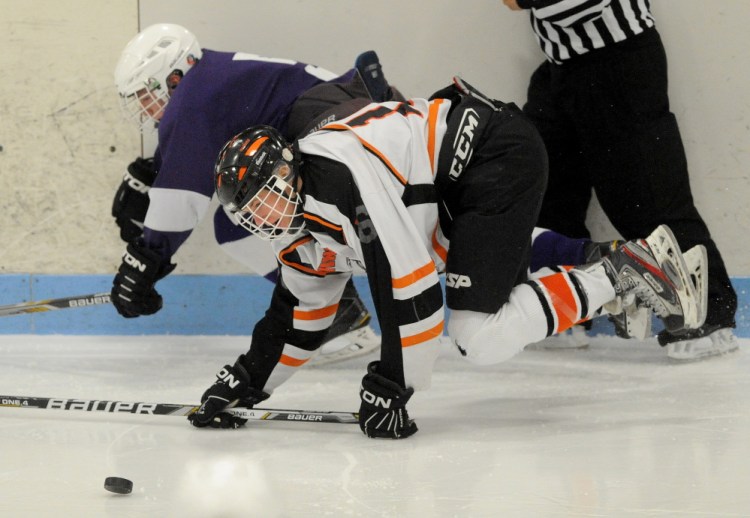 Winslow High School’s Jacob Trask (16) battles for the puck with Hampden’s Jordan Dysart during an Eastern B quarterfinal Tuesday at Sukee Arena in Winslow. The Black Raiders won 3-2.