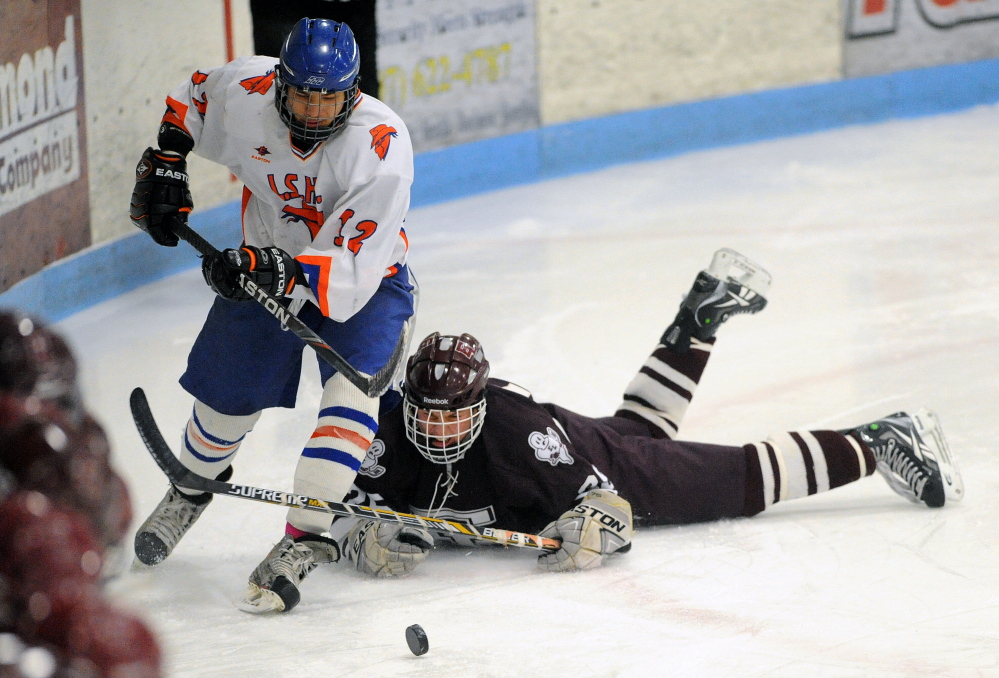 Staff photo by Michael G. Seamans 
 Lawrence/Skowhegan's Alex Paul (12) skates away from Edward Little's Ryan Raby (25) during an Eastern A quarterfinal Tuesday night at Sukee Arena.