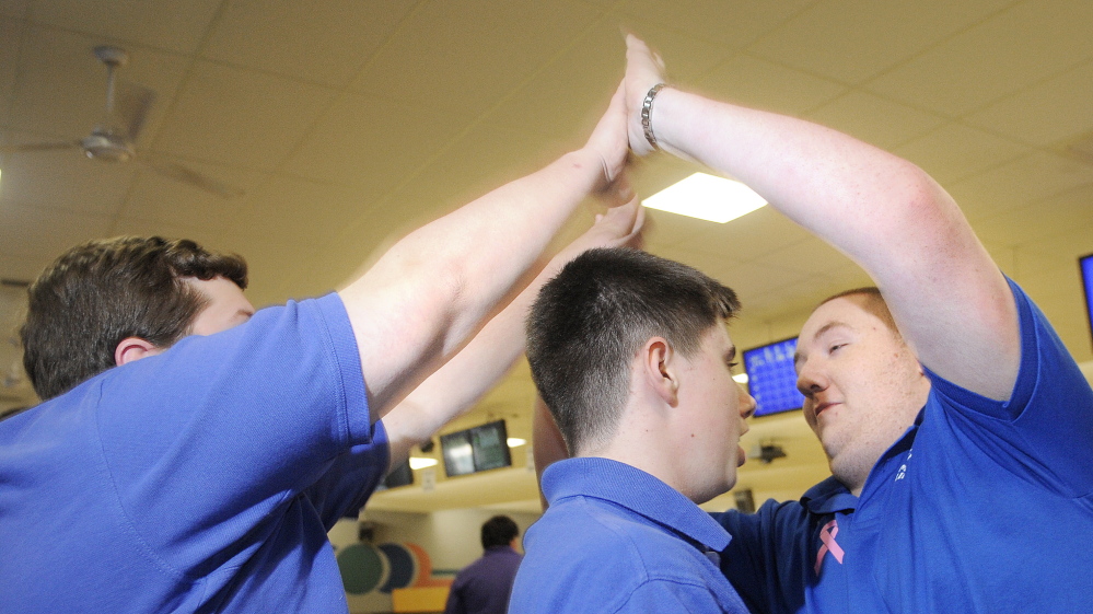 Tresten Bergeron, right, salutes Lawrence teammates during a match Wednesday at Sparetime Recreation in Hallowell. Bergeron recently won the individual state bowling championship.
