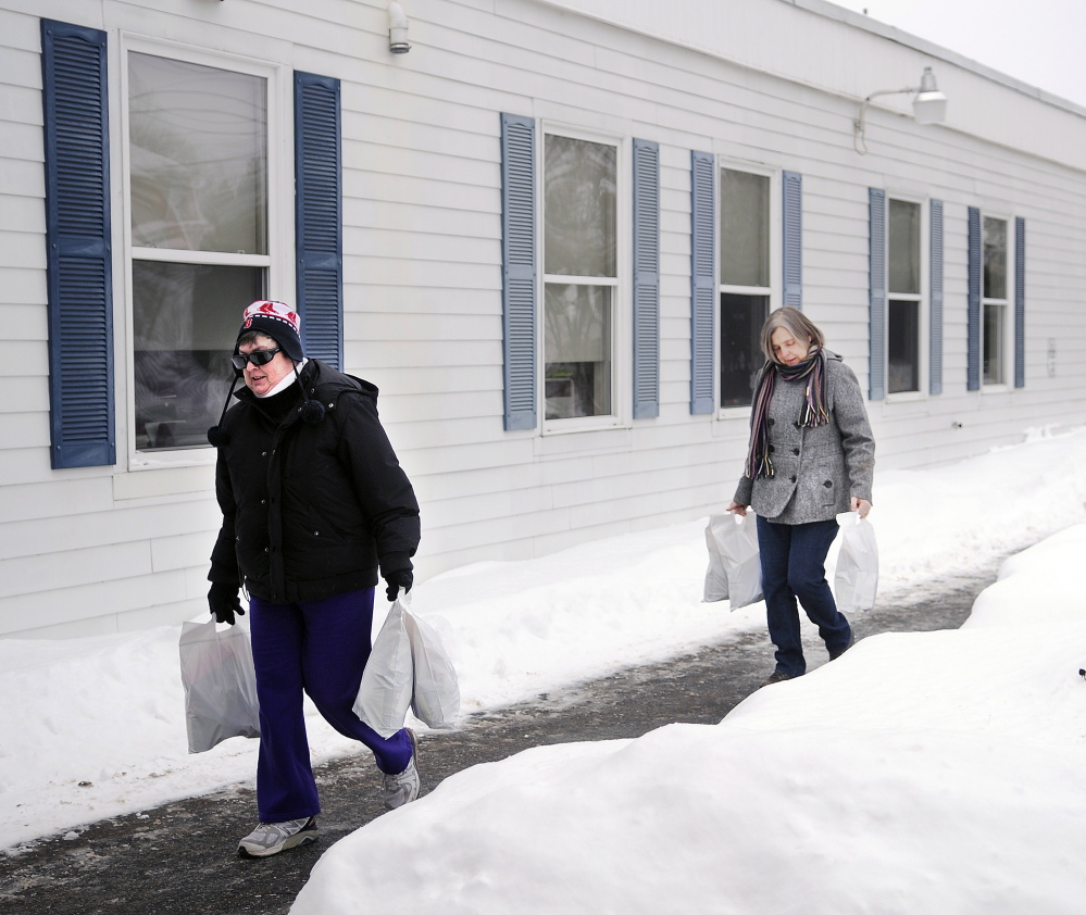 Connie LaFlamme, right, and her sister-in-law, Debbie LaFlamme, carry bags of groceries into the Hamlin School in Randolph on Thursday. The volunteers deliver groceries through Food for Thought to provide supplemental nutrition to students in the Gardiner area school district.