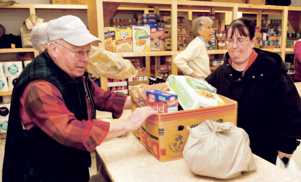 Volunteer Bob Veilleux helps slide a box of food for Anne Robinson on the first day of operation for the new Fairfield Interfaith Food Pantry on Thursday. In the background volunteer Louise O’Brien waits to assist another client.