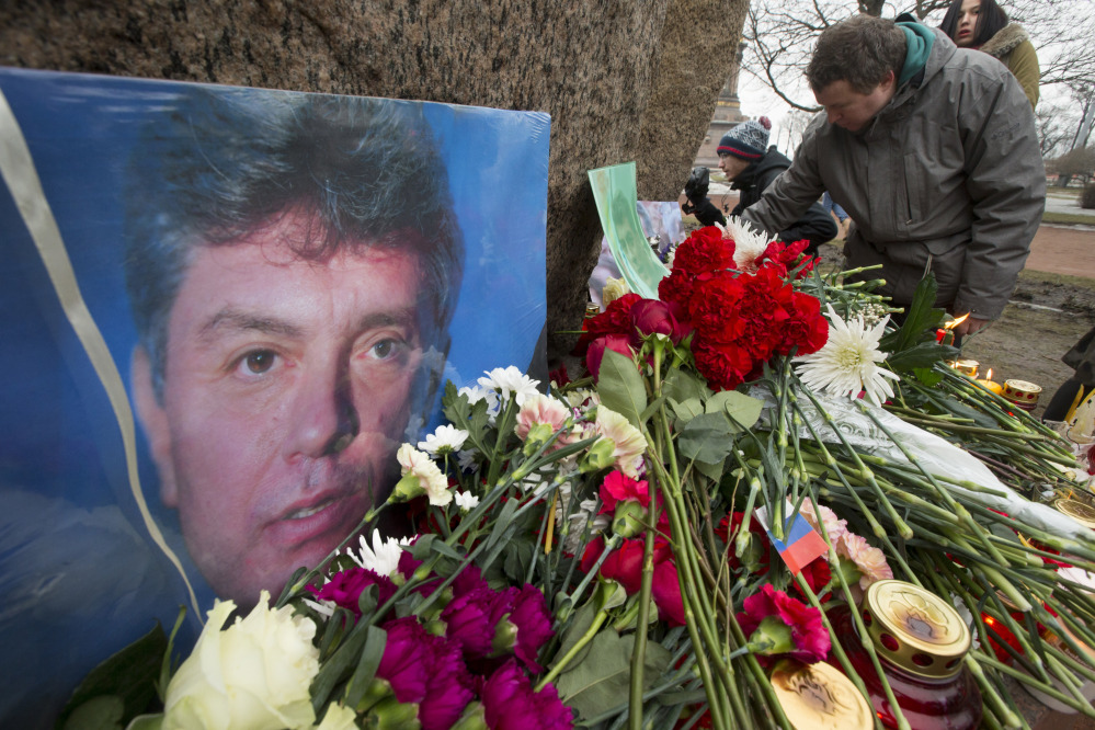 People lay flowers in memory of Boris Nemtsov, seen at left, at the monument of political prisoners ‘Solovetsky Stone’ in central St. Petersburg, Russia, Saturday.