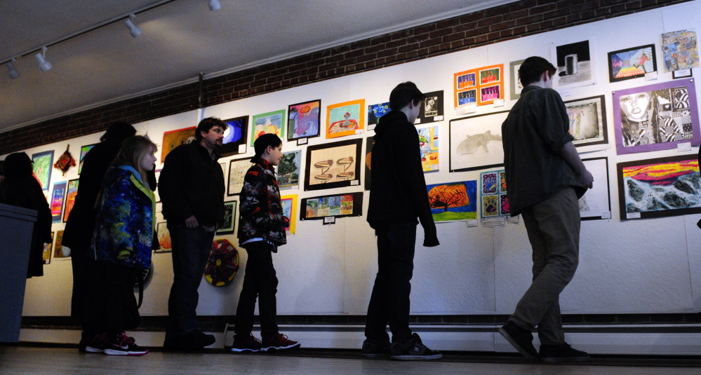 Showgoers inspect the 200 works on display at the opening of the Young at Art Show on Saturday at the Harlow Gallery in Hallowell.
