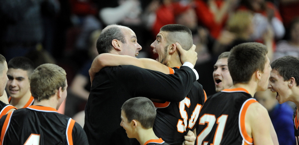 Forest Hills High School head basketball coach Anthony Amero celebrates with Tanner Daigle after defeating Fort Fairfield High School 51-45 in the Class D state championship game Saturday at the Cross Insurance Center in Bangor.